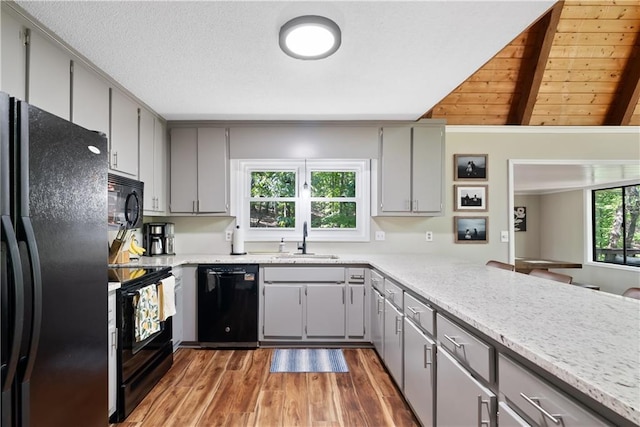 kitchen with sink, lofted ceiling with beams, wooden ceiling, gray cabinets, and black appliances