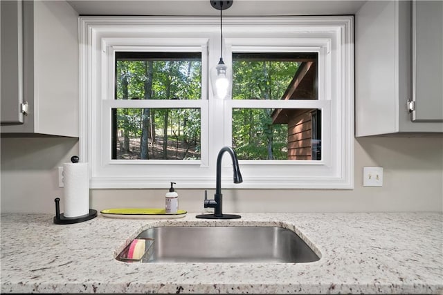 kitchen featuring light stone counters and sink