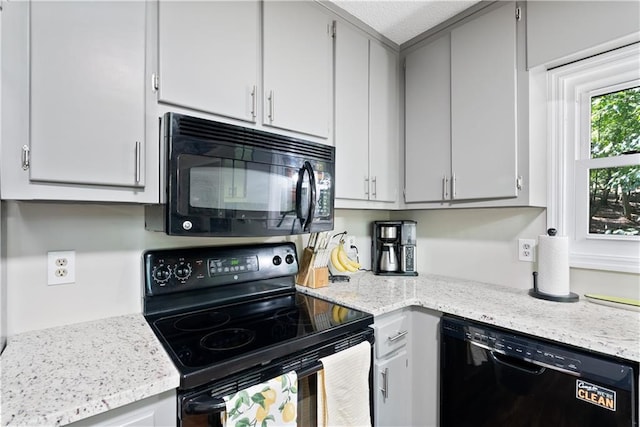 kitchen featuring light stone countertops and black appliances