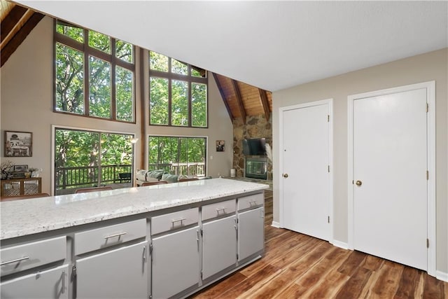 kitchen with wood ceiling, dark wood-type flooring, gray cabinetry, high vaulted ceiling, and light stone countertops