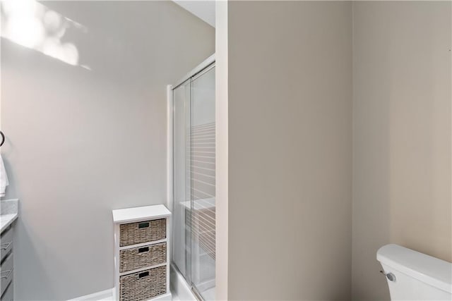 bathroom with vanity, a shower with door, and toilet