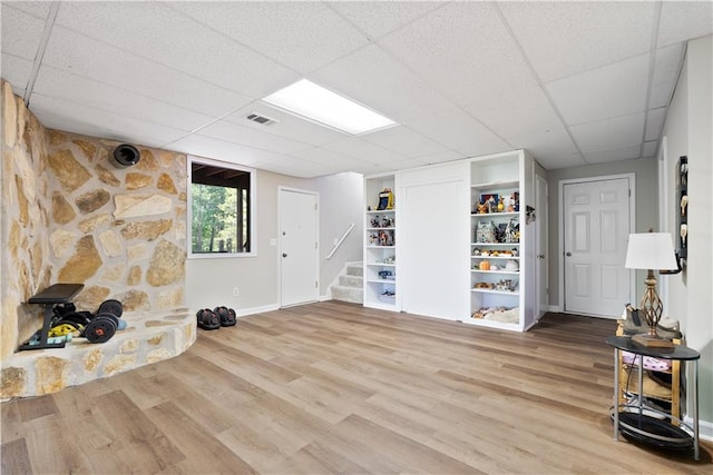 basement with built in shelves, a paneled ceiling, and hardwood / wood-style flooring