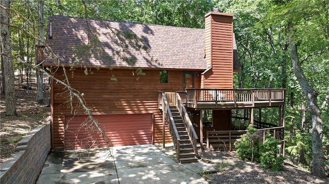 rear view of property featuring a wooden deck and a garage