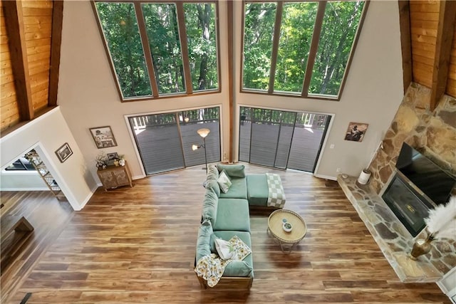 living room featuring a high ceiling, a stone fireplace, and hardwood / wood-style floors