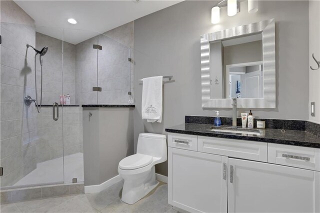 bathroom featuring tile patterned flooring, vanity, a shower with shower door, and toilet