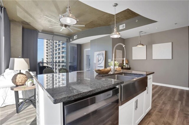 kitchen featuring tasteful backsplash, white cabinets, dark stone counters, and wall chimney range hood