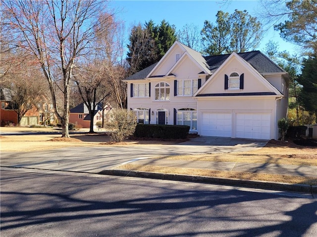 colonial inspired home featuring a garage, driveway, and stucco siding