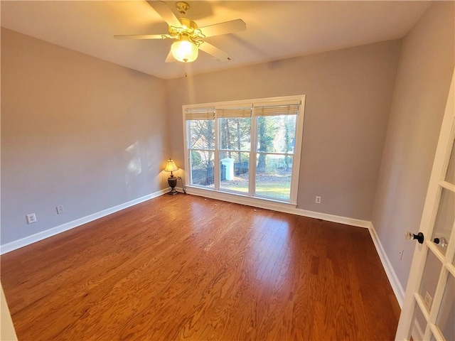 empty room featuring ceiling fan, baseboards, and wood finished floors