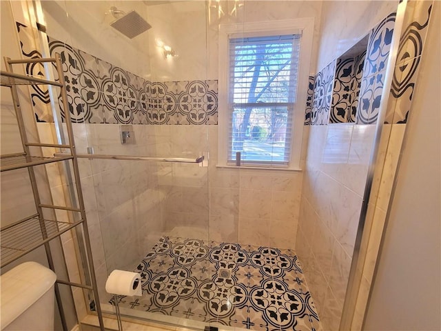 full bathroom with a tile shower and toilet