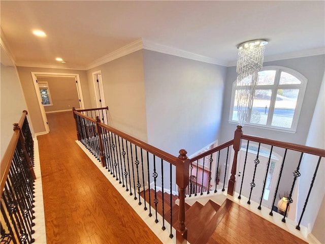 hallway with crown molding, an upstairs landing, wood finished floors, a chandelier, and baseboards