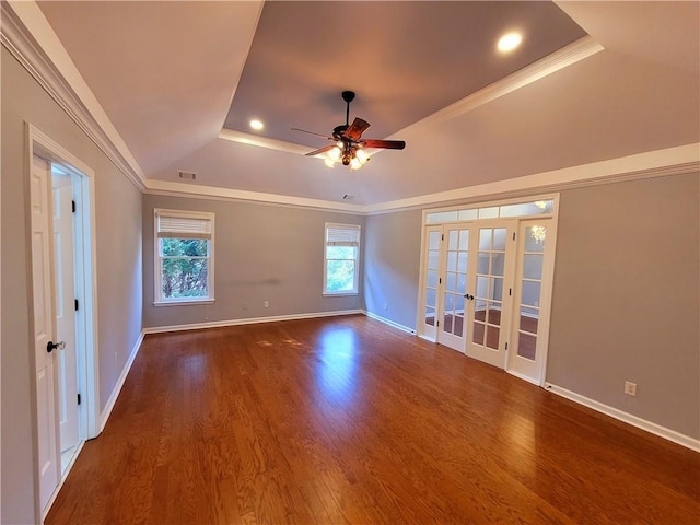 empty room featuring wood finished floors, a raised ceiling, and crown molding