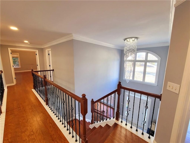 stairway featuring a chandelier, ornamental molding, wood finished floors, and baseboards