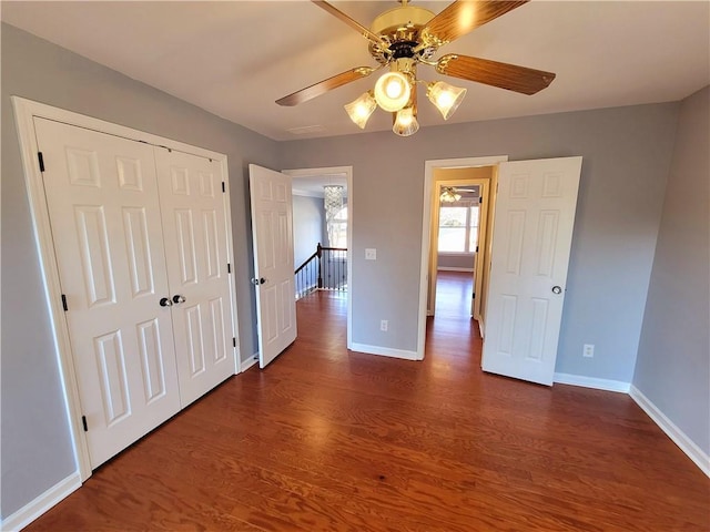 unfurnished bedroom with a ceiling fan, a closet, baseboards, and dark wood-style flooring