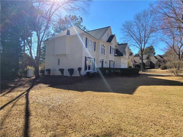 view of side of property with a yard, roof with shingles, and stucco siding