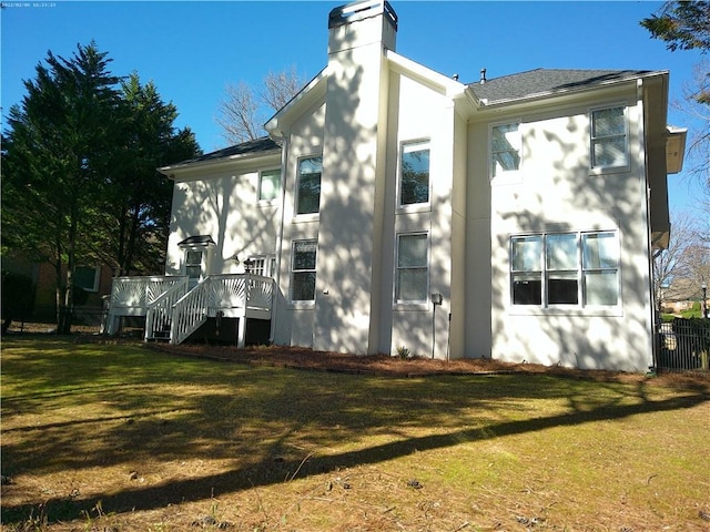 view of home's exterior featuring a lawn, a chimney, and a wooden deck