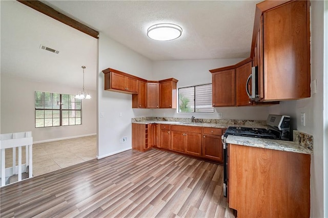 765 Martin Rd, Stone Mountain, GA 30088 - kitchen with gas stove, vaulted ceiling, brown cabinets, stainless steel microwave, and a textured ceiling
