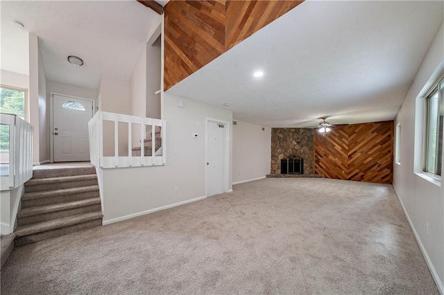 765 Martin Rd, Stone Mountain, GA 30088 - unfurnished living room featuring carpet, stairway, ceiling fan, wood walls, and a fireplace