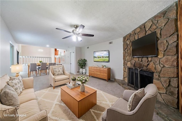 765 Martin Rd, Stone Mountain, GA 30088 - living area featuring a stone fireplace, light colored carpet, a textured ceiling, and a ceiling fan
