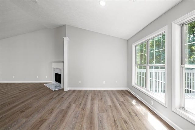 unfurnished living room featuring lofted ceiling, wood finished floors, a premium fireplace, and baseboards