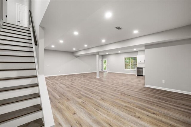 basement with recessed lighting, light wood-style floors, stairs, and baseboards