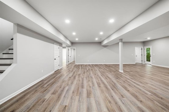 below grade area featuring recessed lighting, light wood finished floors, baseboards, and stairs