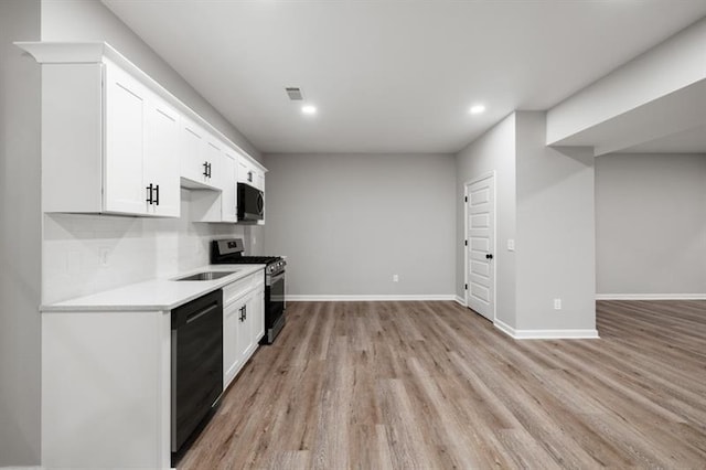 kitchen featuring stainless steel gas range, dishwasher, light wood finished floors, light countertops, and baseboards