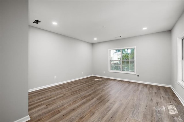 spare room featuring wood finished floors, baseboards, and recessed lighting