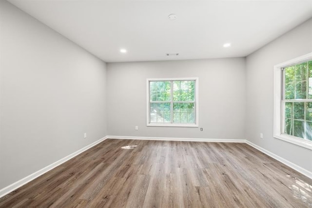 unfurnished room featuring wood finished floors, baseboards, and recessed lighting