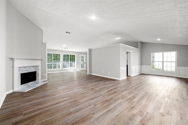 unfurnished living room featuring wood finished floors, vaulted ceiling, a fireplace, recessed lighting, and a textured ceiling
