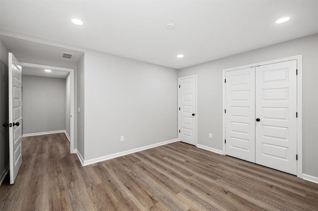unfurnished bedroom featuring wood finished floors, recessed lighting, baseboards, and a closet