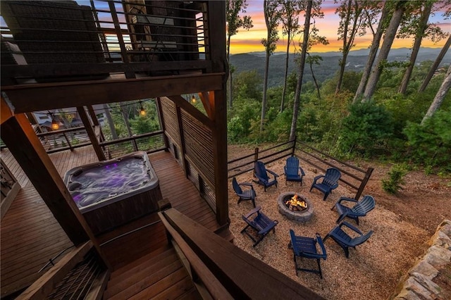 wooden balcony featuring a hot tub, a deck, and a fire pit