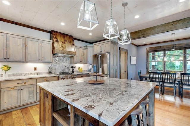 kitchen with a kitchen island, pendant lighting, high end refrigerator, and light stone counters