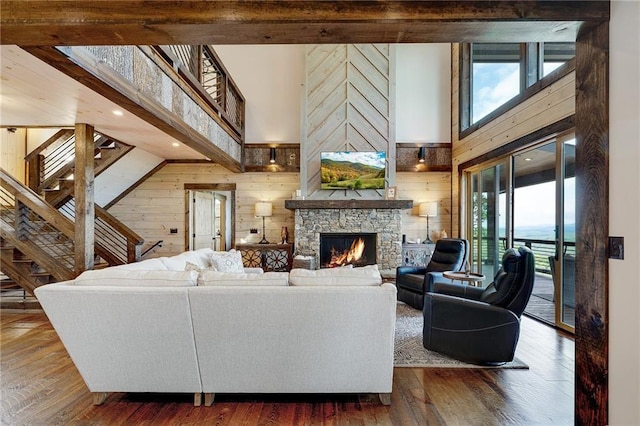 living room with a fireplace, wooden walls, dark hardwood / wood-style flooring, and a high ceiling