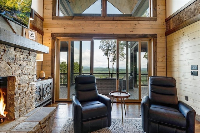 living area with high vaulted ceiling, a fireplace, and wooden walls