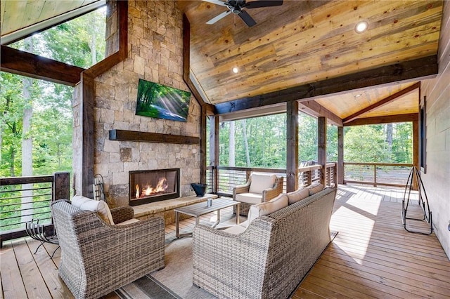 sunroom with ceiling fan, lofted ceiling, and an outdoor stone fireplace