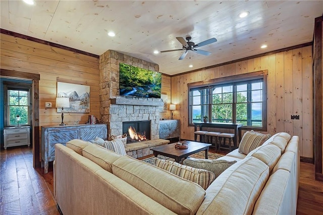 living room featuring a fireplace, dark wood-type flooring, wooden walls, and ceiling fan