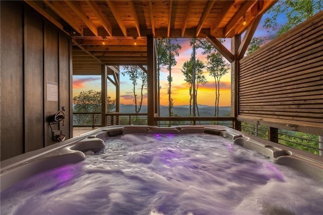 patio terrace at dusk featuring a hot tub and a water view