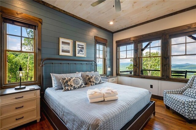 bedroom featuring a mountain view, dark wood-type flooring, wooden ceiling, and ceiling fan