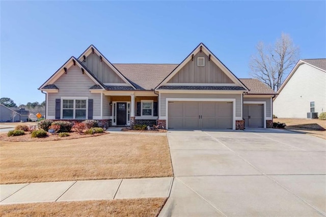 craftsman-style house featuring driveway, an attached garage, a front lawn, board and batten siding, and brick siding