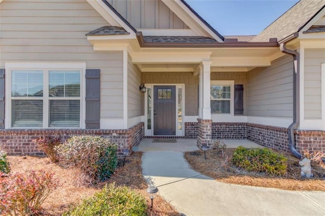 property entrance with covered porch, board and batten siding, and brick siding