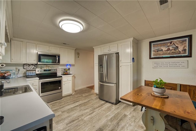 kitchen with light wood-type flooring, stainless steel appliances, white cabinetry, and sink