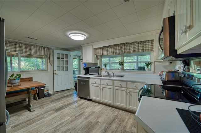 kitchen with light hardwood / wood-style flooring, sink, appliances with stainless steel finishes, and white cabinets