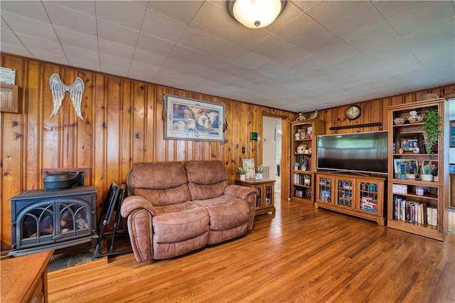 living room featuring a wood stove, hardwood / wood-style floors, and wooden walls