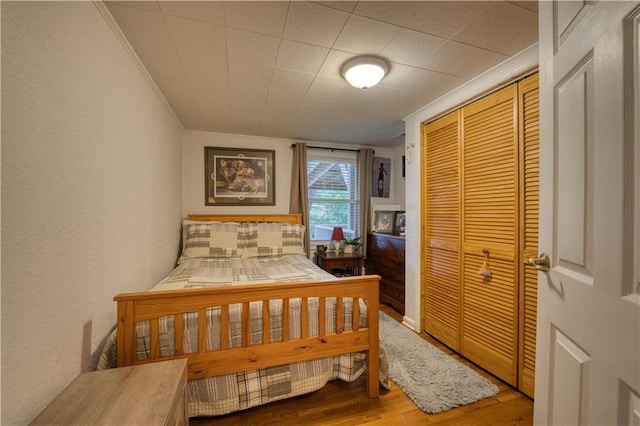 bedroom with crown molding, a closet, and hardwood / wood-style floors