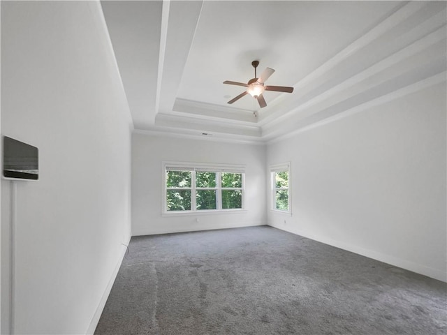 empty room with baseboards, a raised ceiling, ceiling fan, crown molding, and carpet flooring