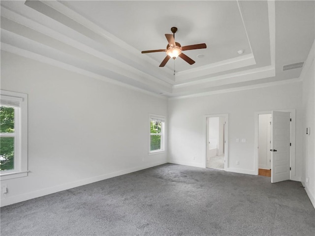 carpeted empty room featuring visible vents, a tray ceiling, ceiling fan, and baseboards