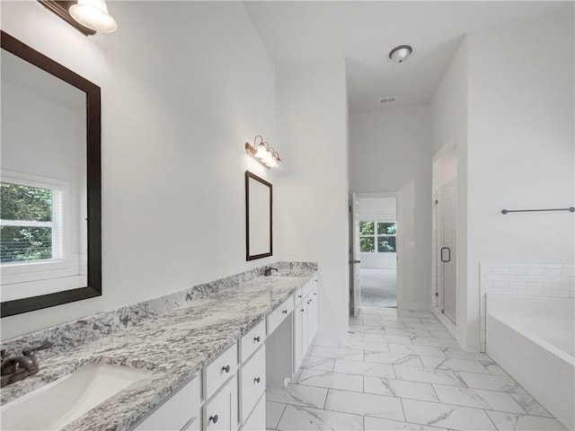 full bath with a bath, marble finish floor, a healthy amount of sunlight, and a sink