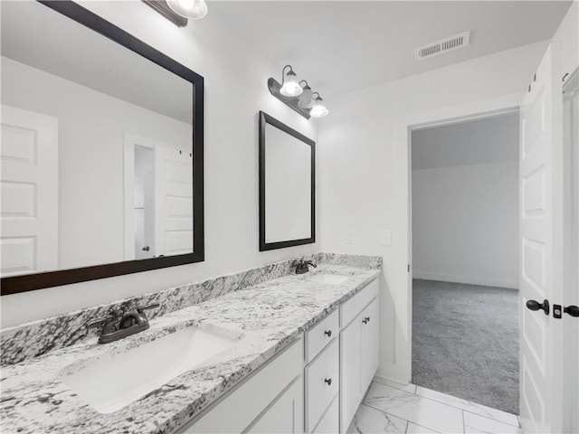 bathroom featuring marble finish floor, double vanity, a sink, and visible vents