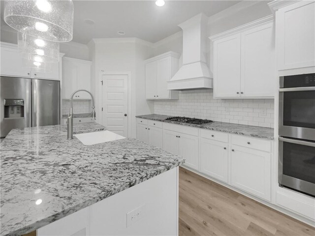 kitchen with light hardwood / wood-style flooring, backsplash, stainless steel appliances, sink, and custom exhaust hood