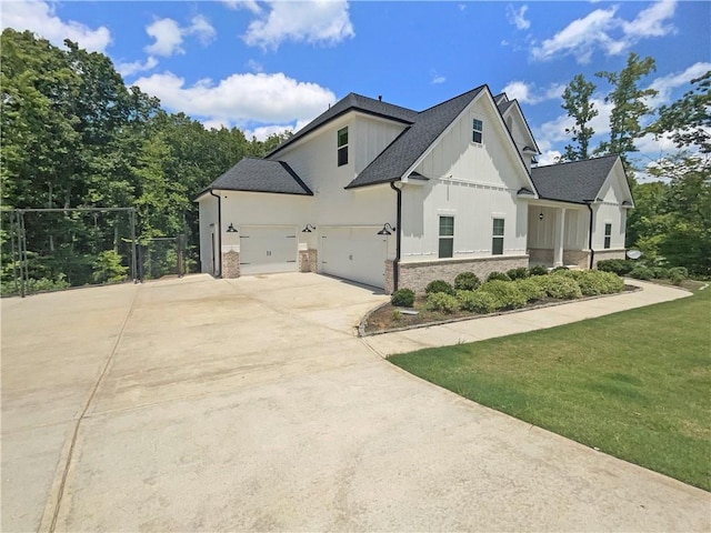 modern farmhouse style home with an attached garage, a shingled roof, driveway, a front lawn, and board and batten siding